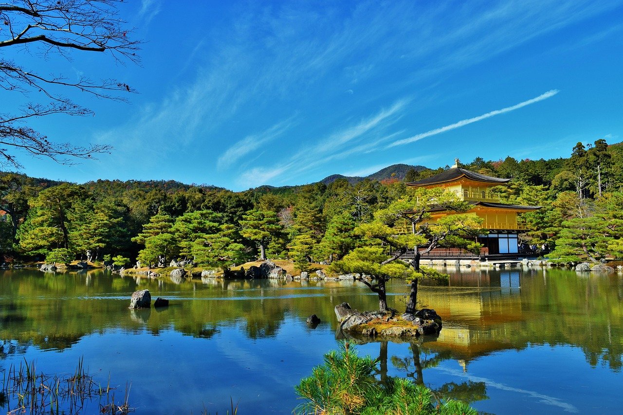 A golden temple in Southeast Asia surrounded by lush greenery and a clear blue sky.