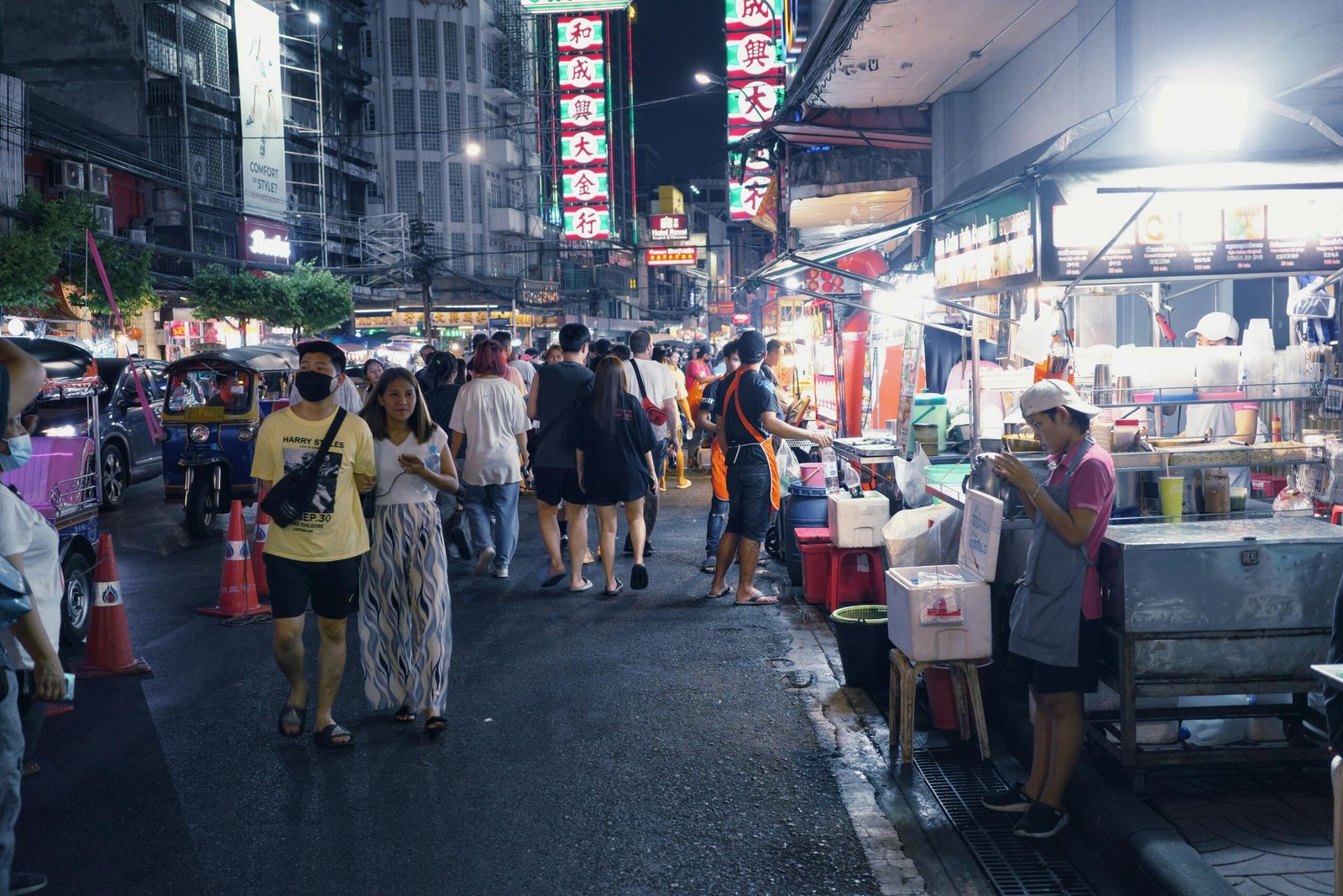 A vibrant street market in Bangkok with colorful food stalls and busy crowds.
