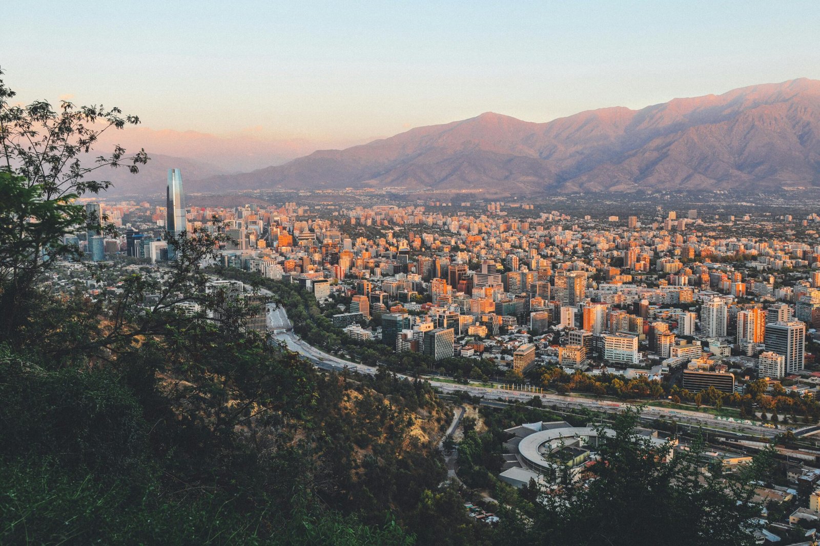The skyline of Santiago, Chile, with the Andes Mountains in the background under a clear blue sky.