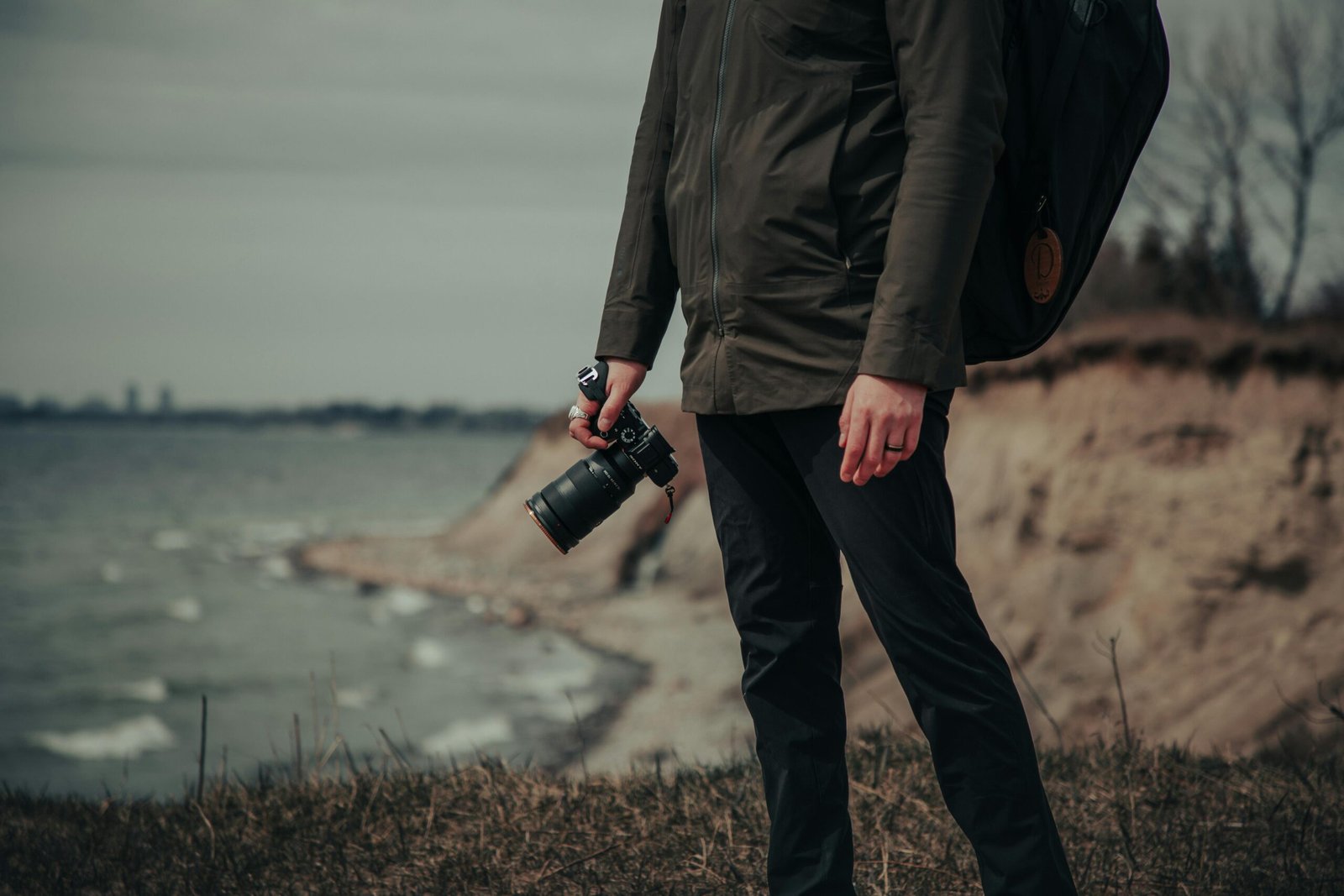 pexels-photo-9965136-9965136 A photographer stands on the cliffs of Whitby, Canada, capturing the serene lake view.