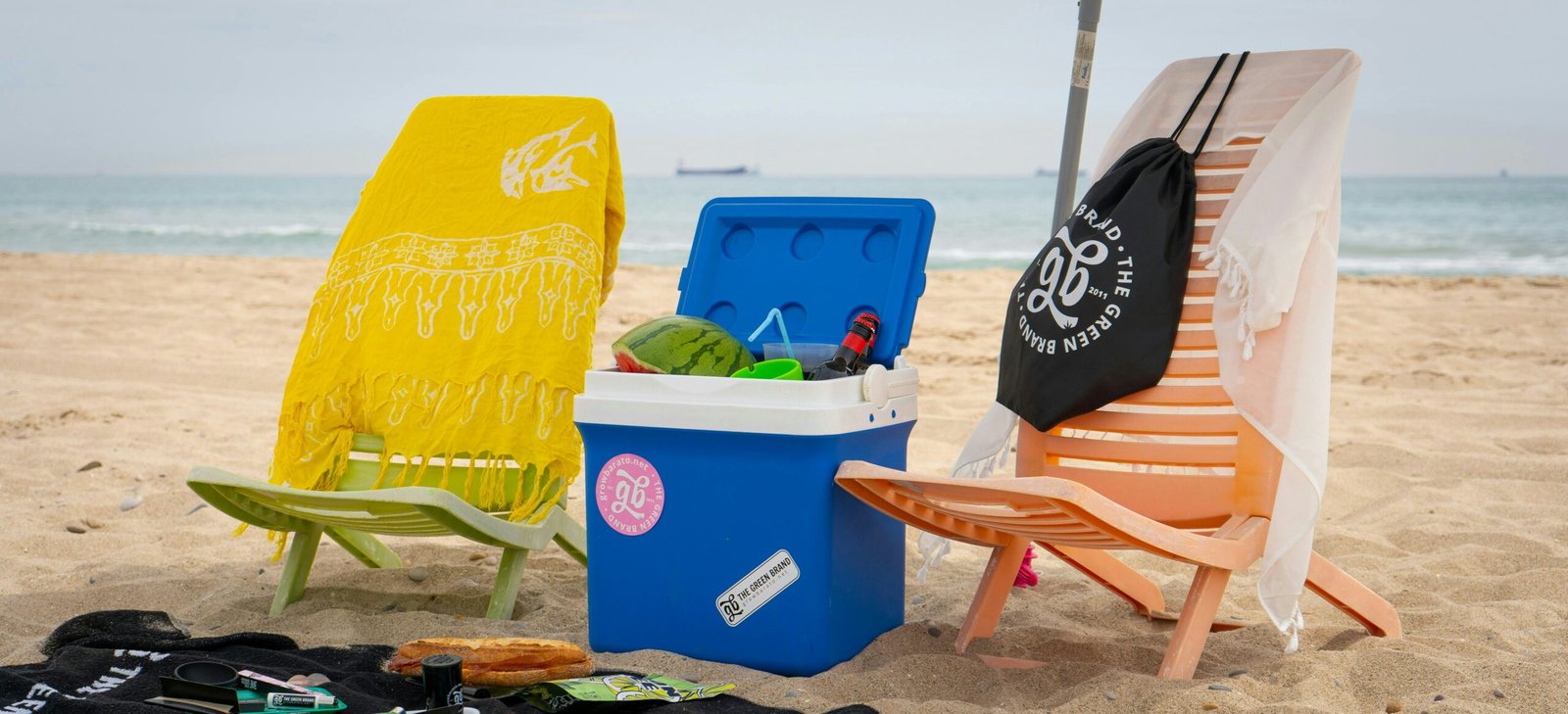 A family’s travel essentials, including a suitcase, beach toys, and sunscreen, laid out on a sandy beach.