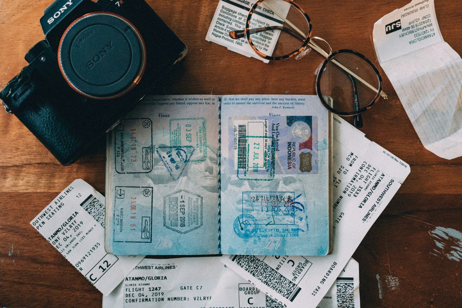 A passport with visa stamps and travel documents neatly arranged on a desk.