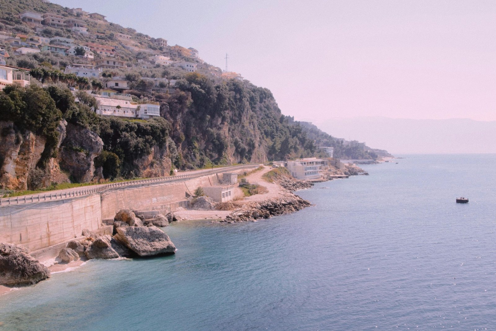 A picturesque Albanian Riviera village with colorful boats and mountainous backdrop.