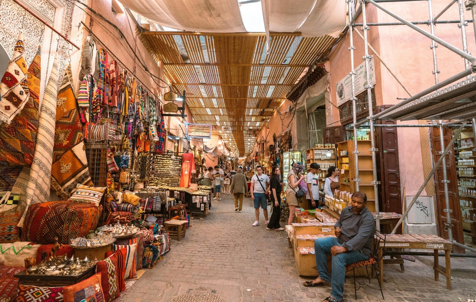 A bustling souk in Marrakech with colorful spices, textiles, and lanterns on display.