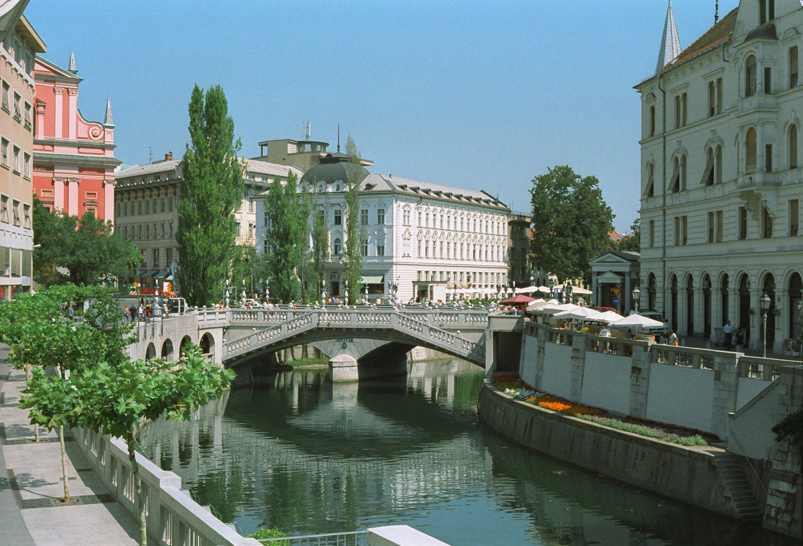 The car-free Triple Bridge in Ljubljana, Slovenia, with the Ljubljanica River and charming cafes in the background.