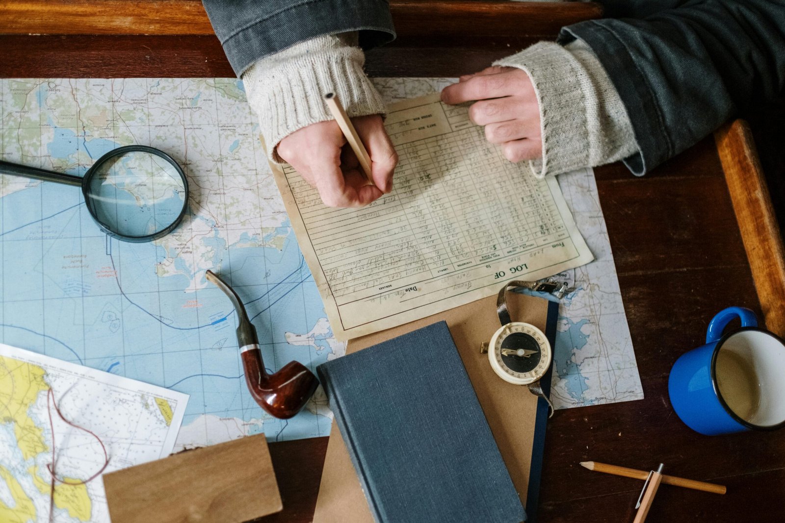 A traveler planning a route with a map and compass on a rustic table.