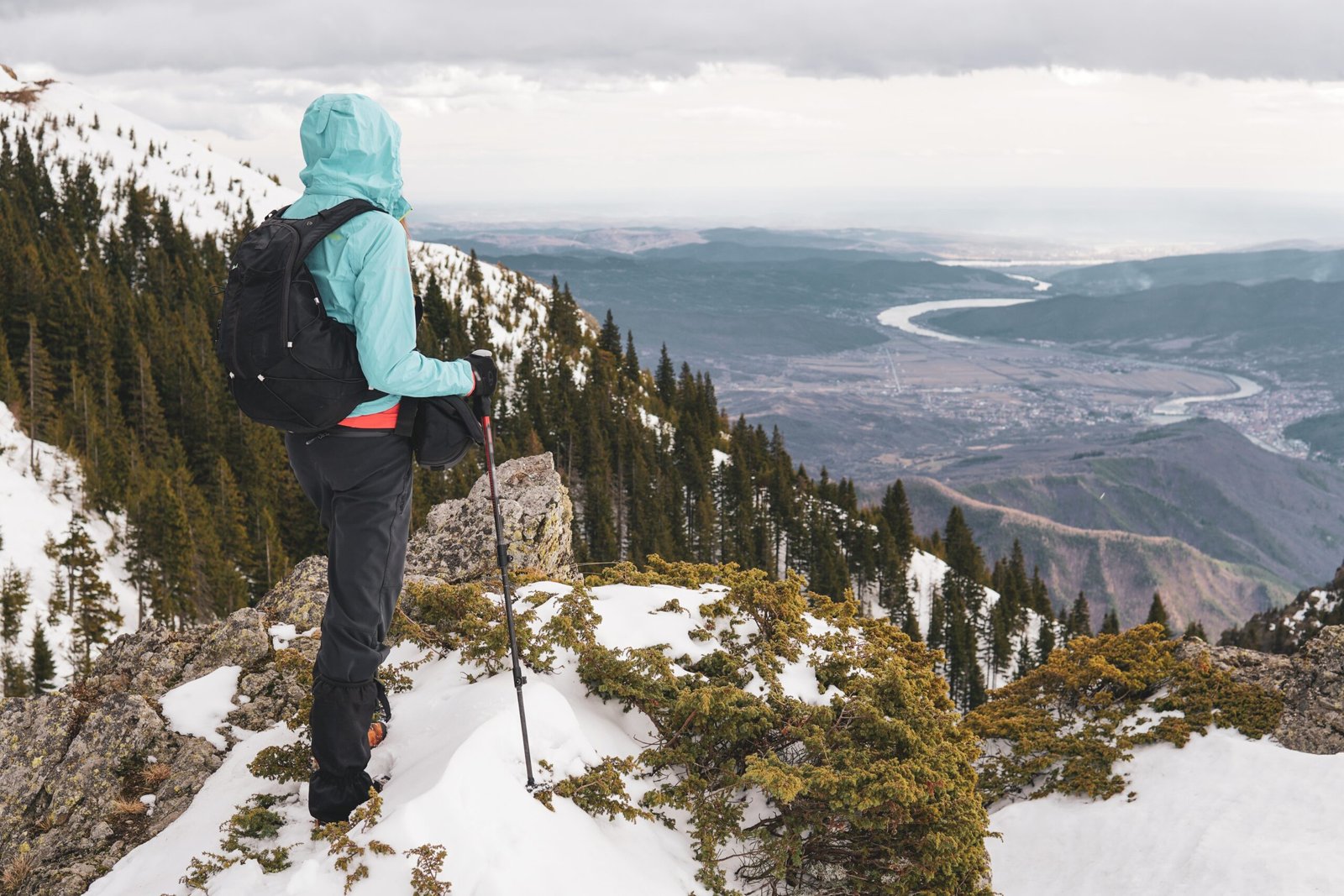 A hiker traversing a rugged trail in Romania’s Carpathian Mountains, surrounded by snow-capped peaks.