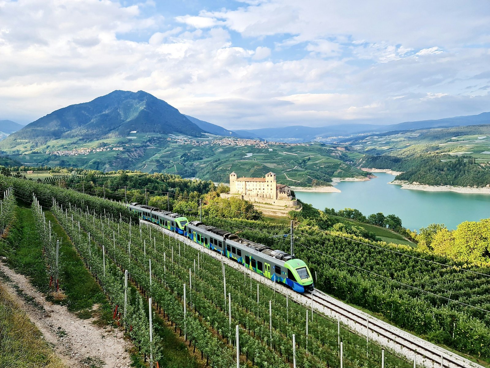 A sleek electric train traveling through a scenic European countryside, symbolizing sustainable summer travel.