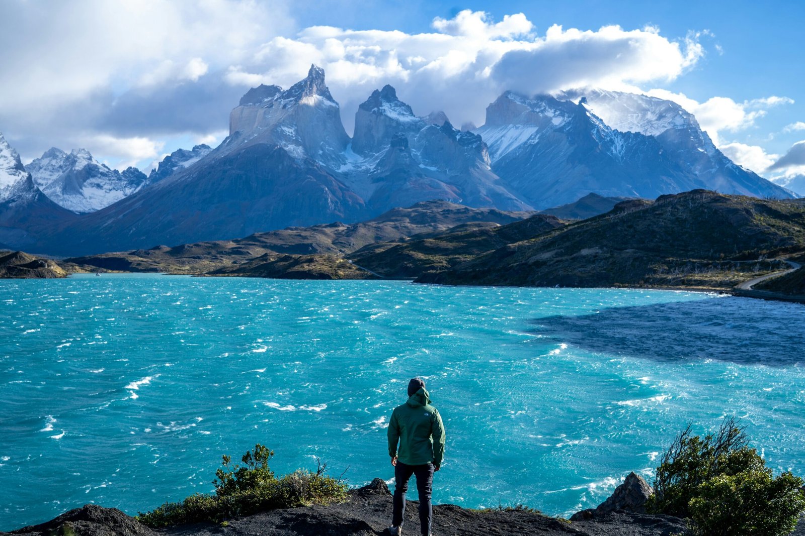 A solo traveler with outdoor equipment and safety gear, exploring a South American summer landscape.