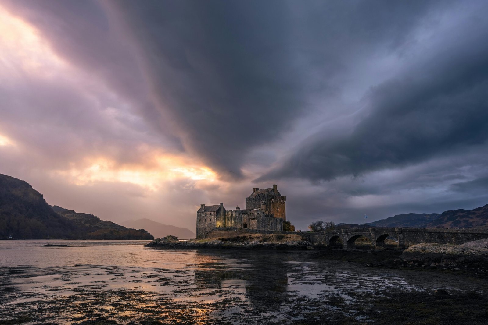 A breathtaking view of Eilean Donan Castle silhouetted against a dramatic sunset sky.