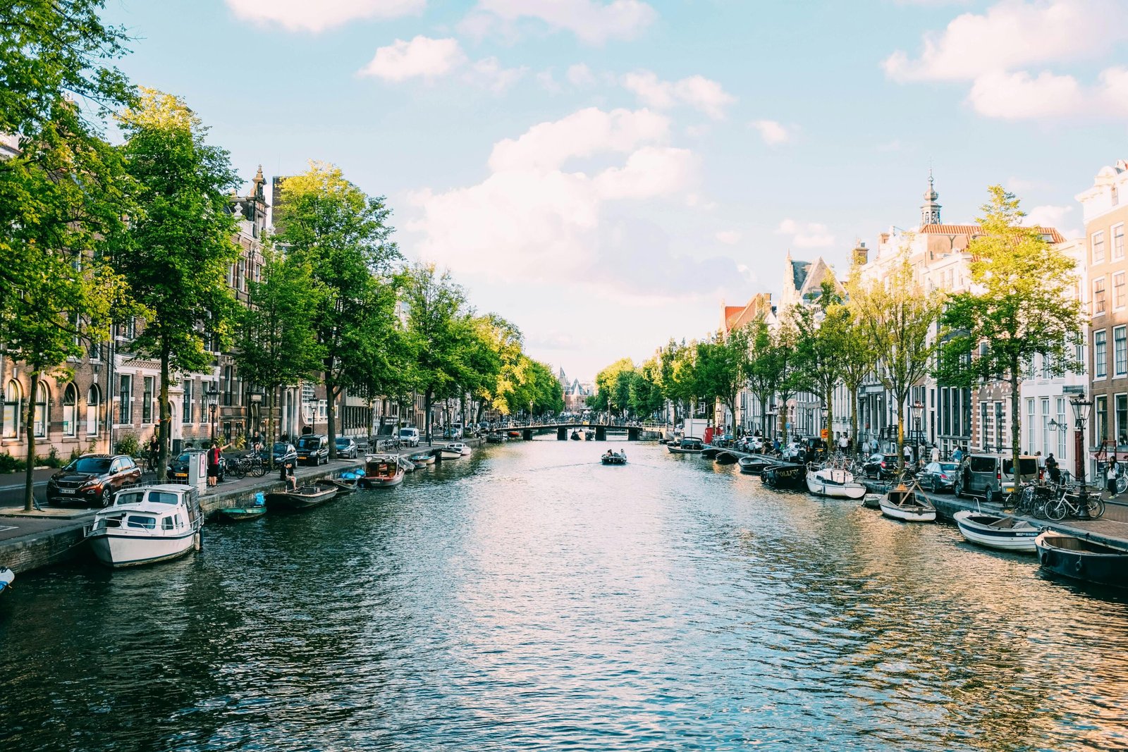 Picturesque Amsterdam canal lined with boats and historic buildings under a clear sky.