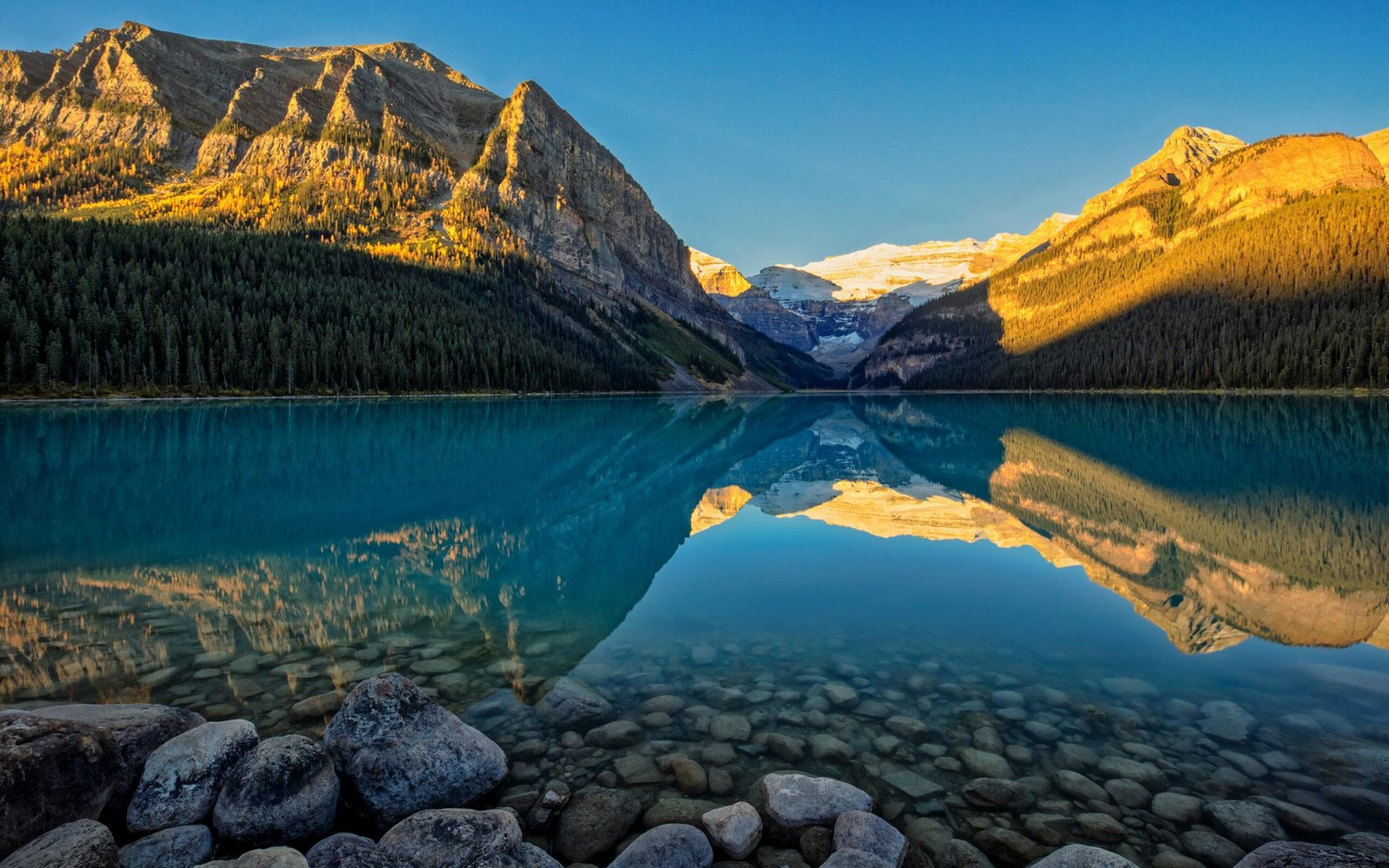 Beautiful sunrise reflection on Lake Louise, capturing the serene landscape of mountains and water in Canada.