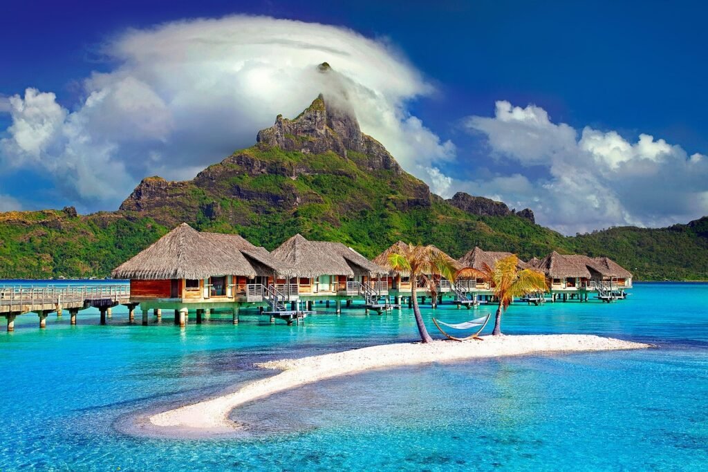 A stunning aerial view of Bora Bora, showing the central island with Mount Otemanu and the surrounding turquoise lagoon dotted with overwater bungalows.