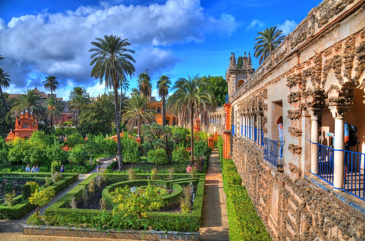 The stunning gardens of the Royal Alcázar of Seville, with its intricate Moorish architecture and lush greenery.