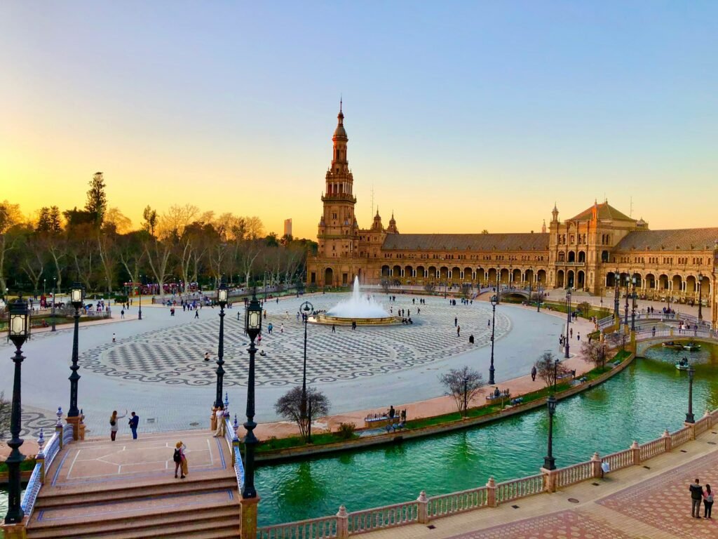 A vibrant, sun-drenched shot of Plaza de España in Seville, with its beautiful tile work and canal.