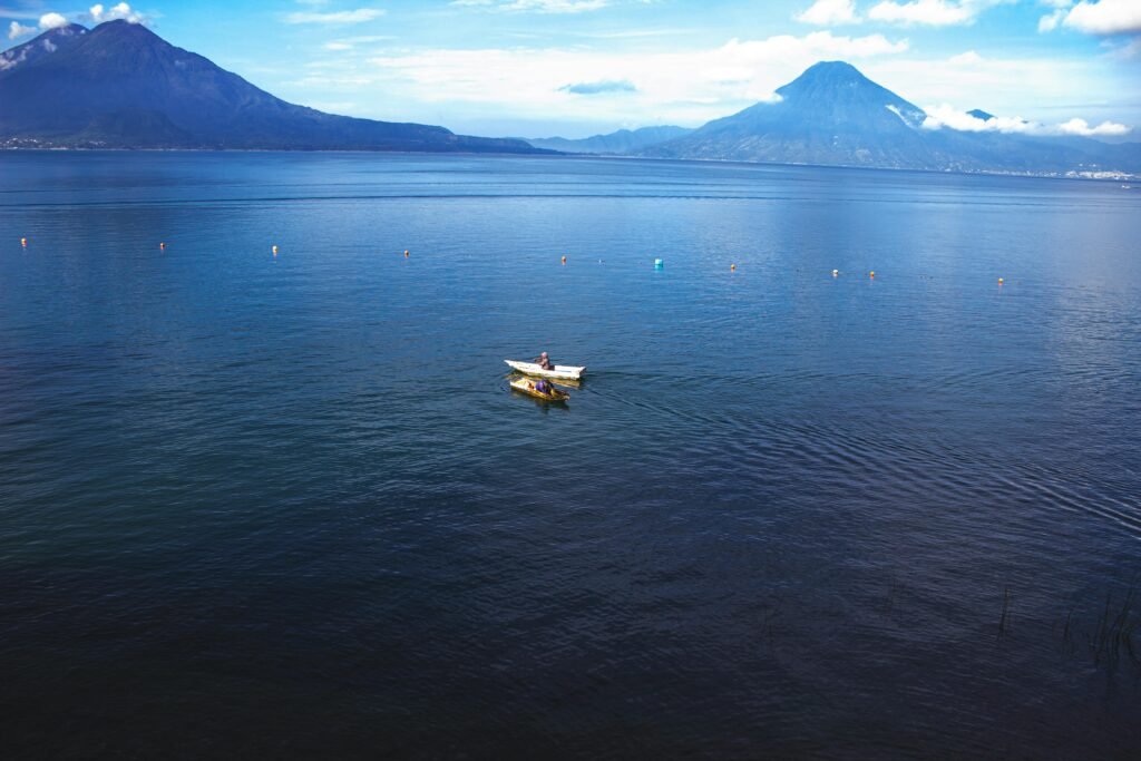 A tranquil scene of a boat on Lake Atitlán, Guatemala with mountains in the background.