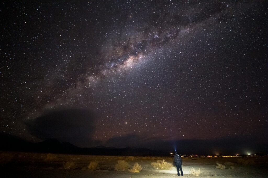 A lone man stands under the stunning Milky Way in the Atacama Desert, Chile, at night.