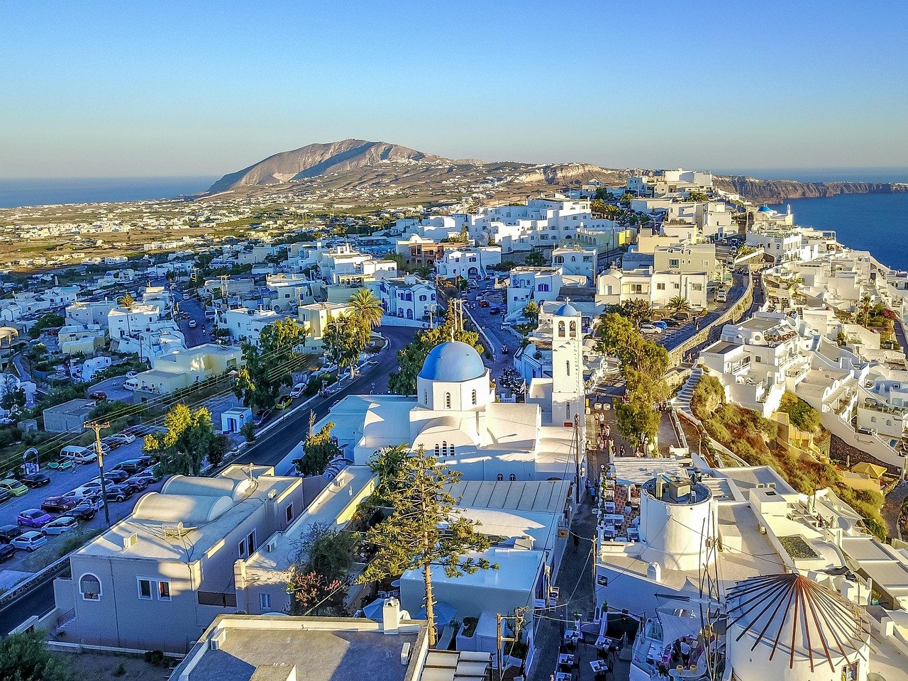 Greek island whitewashed buildings with blue accents in peaceful village setting.