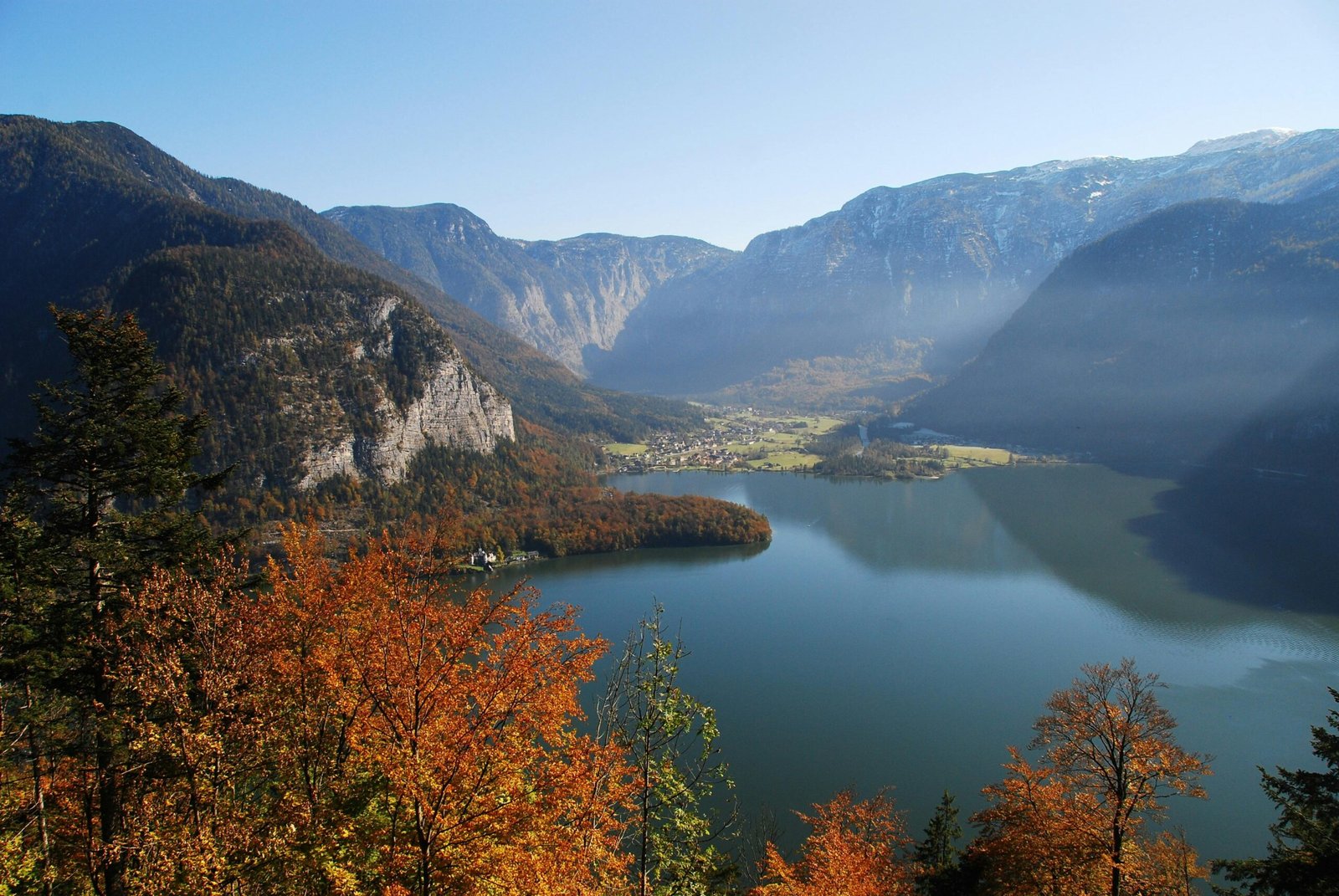 Stunning aerial view of Hallstatt with vibrant autumn foliage and serene lake surrounded by majestic mountains.