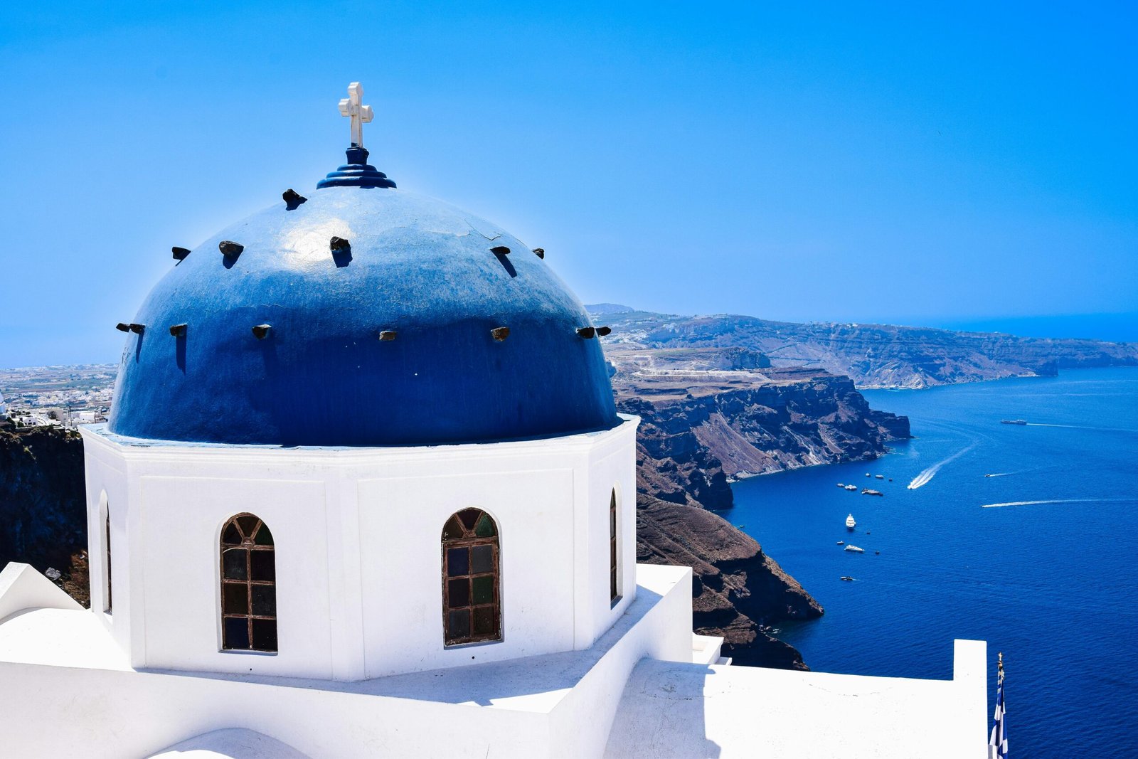 Iconic Greek architecture with a blue dome set against the stunning Santorini coastline.