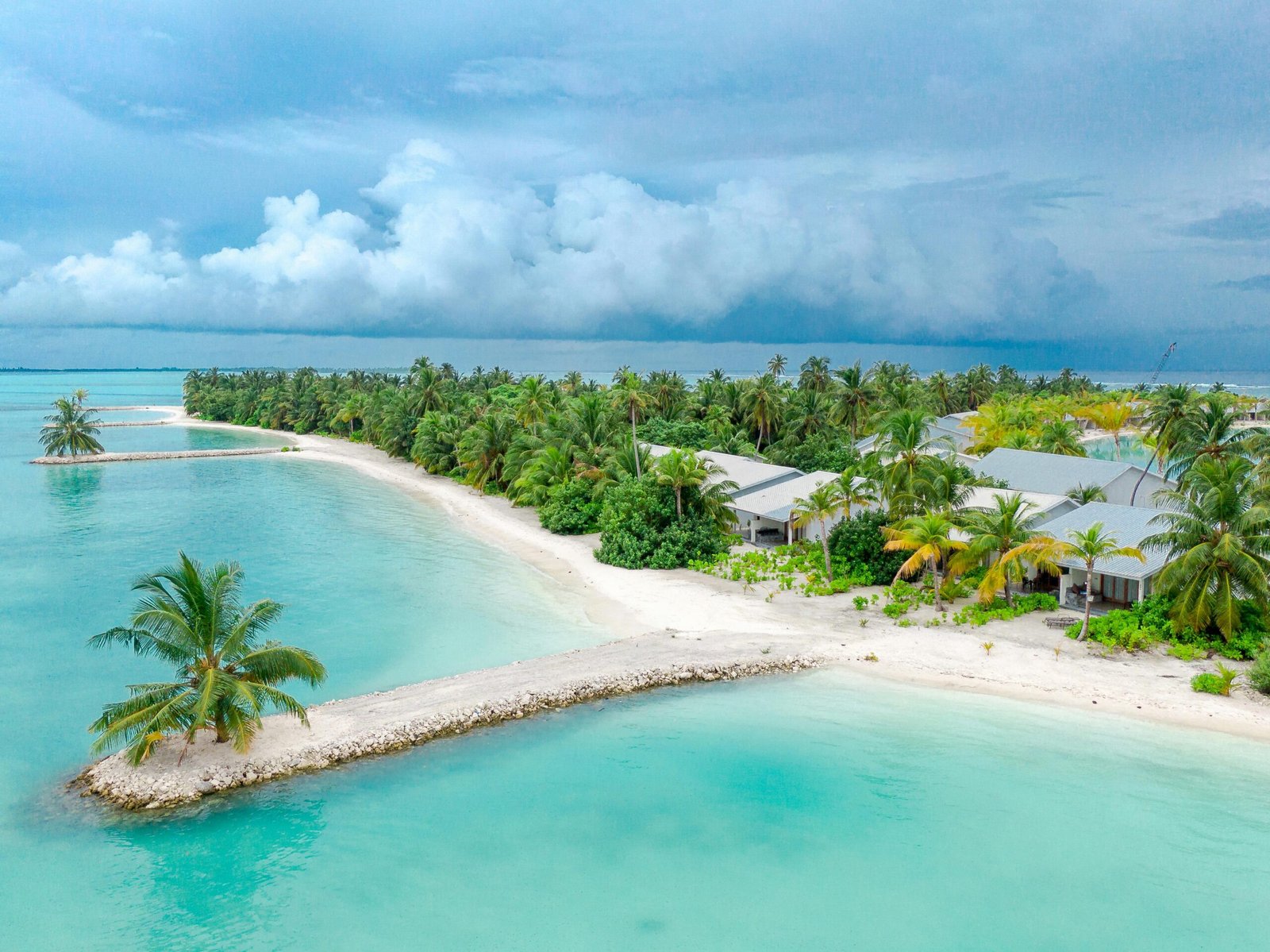 Aerial view of a tropical island with palm trees, turquoise waters, and sandy beaches.